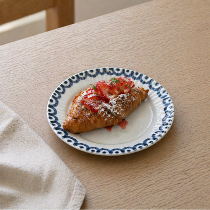 Small plate with a pastry topped with strawberries on a wooden table