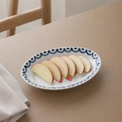 Sliced apples on a decorative plate with a wavy edge design, placed on a beige surface.