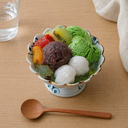 Bowl of assorted ice cream with fruits and a wooden spoon on a wooden table